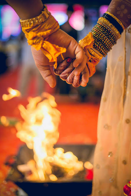 A couple's clasped hands over the sacred wedding fire during a Hindu marriage ceremony.